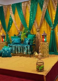 a bed sitting in front of a wall covered in green and gold drapes with lights on it