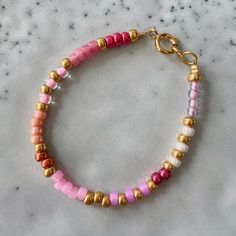 a pink and gold beaded bracelet on a marble surface