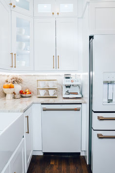 a kitchen with white cabinets and marble counter tops