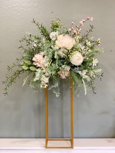 an arrangement of flowers on a gold stand