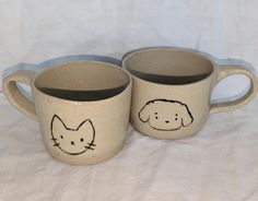 two coffee mugs with cats and dogs drawn on them