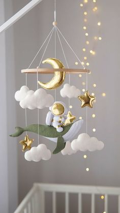 a baby crib mobile with stars, moon and clouds hanging from it's side