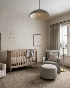 a baby's room with a crib, chair and ottoman