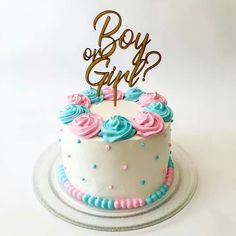 a white cake with blue and pink frosting on top that says boy or girl