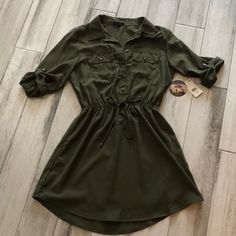 Olive Green Dress. Size Large. Nwt Details: Collar, Button Front, Rolled Button Sleeves Cinched Elastic Waist, Button Front Pockets. Fitted Dresses With Roll-up Sleeves For Fall, Casual Dresses With Roll-up Sleeves For Fall, Casual Green Dresses With Button Cuffs, Khaki Dresses With Buttons For Fall, Casual Green Dress With Button Cuffs, Green Button-up Mini Dress With Button Closure, Fitted Button-up Dress With Roll-up Sleeves, Green Buttoned Mini Dress For Fall, Green Mini Dress With Buttons For Fall