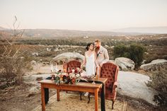 a bride and groom standing in front of a table with candles on it