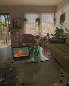 a living room filled with furniture and a laptop computer on top of a glass table