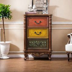 an ornately painted chest of drawers in a room with two chairs and a potted plant