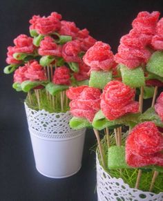 some pink flowers are in white vases with green leaves and grass on the stems