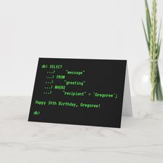 a black card with green text on it sitting next to a vase filled with flowers