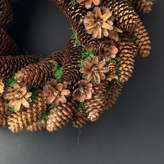 a wreath made out of pine cones and evergreen needles is displayed on a gray background