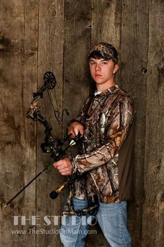 a young man is holding some flowers in front of a wooden wall and posing for the camera