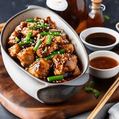 a bowl filled with meat and vegetables next to dipping sauces on a wooden cutting board