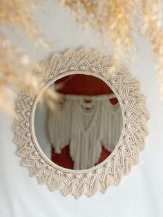 a round mirror sitting on top of a white table next to dry grass and dried flowers