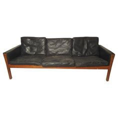 a black leather couch sitting on top of a wooden frame