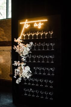 a neon sign with flowers and wine glasses