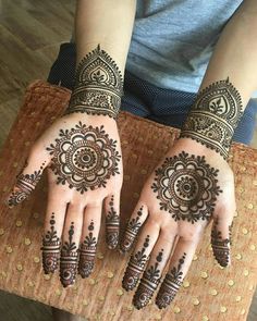 two hands with henna tattoos on them, one is showing off the intricate design