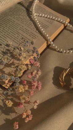 an open book with pearls and flowers on it next to a pair of bracelets