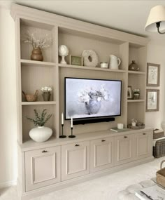 a large flat screen tv sitting on top of a wooden shelf in a living room