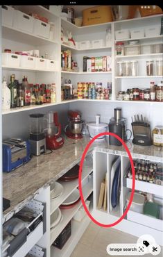 a kitchen with white cabinets and shelves filled with food