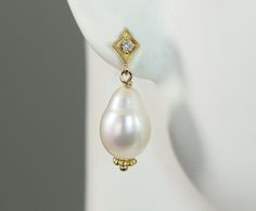 Lovely tear drop shaped baroque freshwater pearls drop from a diamond set in a diamond shaped post setting all in 14k yellow solid gold. Pearl is the birthstone for June and the 3rd and 30th wedding anniversary gemstone. Diamond is the birthstone for April and the 10th and 60th wedding anniversary gemstone. The natural color cultured freshwater pearls measures 12 x 9.6 mm tear drop shape The natural diamonds total weight is .05 carats G-H color VS2 clarity Metal is 14k yellow gold The total leng Diamond Pearl Drop Earrings For Anniversary, Anniversary Drop Pearl Earrings With Diamonds, Anniversary Diamond Pearl Drop Earrings, Pear Shaped Diamond Jewelry With Pearl Drop, High Luster Drop Pearl Earrings For Anniversary, High Luster Teardrop Pearl Earrings, Anniversary Teardrop Pearl Earrings With High Luster, Anniversary Diamond Drop Pearl Earrings, Diamond White Pear Pearl Drop Earrings