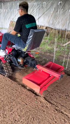 a man riding on the back of a red tractor