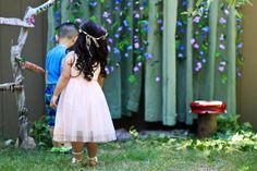 two children standing in front of a fence with flowers on it