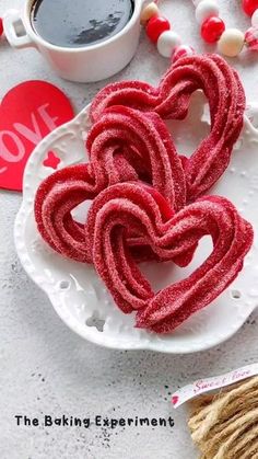 two heart shaped pretzels sitting on a plate next to a cup of coffee