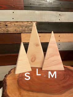 three wooden christmas trees with the word slm in white letters on top of them