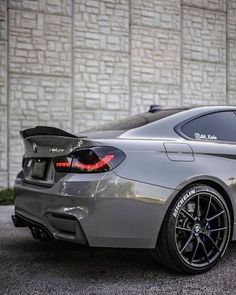 a silver car parked in front of a white brick building with black rims on it