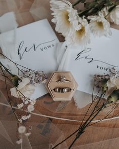 two wedding rings sitting on top of each other next to some flowers and paper napkins