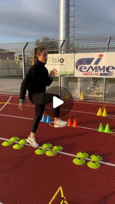 a woman is running on a track with cones around her and an orange cone in the foreground