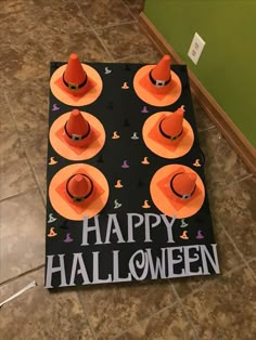 an orange hat sits on top of a black sign that says happy halloween with other hats around it