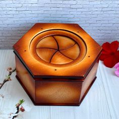 a wooden box sitting on top of a white table next to red and pink flowers