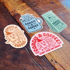 three stickers that are on top of a wooden table and one has a coffee cup