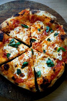 the pizza is cut into eight pieces on the wooden board with cheese and spinach