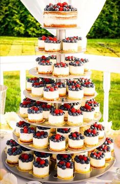 a wedding cake and cupcakes are arranged on a tiered tray in the shape of a tree