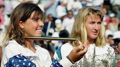 two women standing next to each other holding tennis racquets