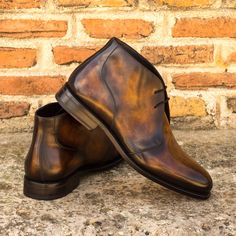 a pair of brown shoes sitting on top of a stone floor next to a brick wall