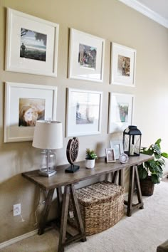 a living room with pictures on the wall and a table in front of some plants