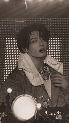 black and white photograph of a man in front of microphones with lights behind him