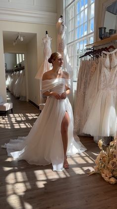 a woman in a white dress standing next to some dresses