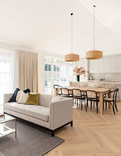 a living room filled with furniture next to a kitchen and dining room table on top of a hard wood floor