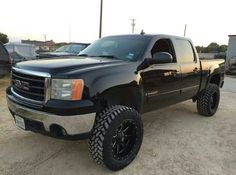 a black truck parked on top of a dirt field