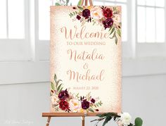 a welcome sign with flowers and greenery sits on an easel in front of a window