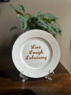 a white and gold plate with live laugh laboratory written on it sitting on a wooden table