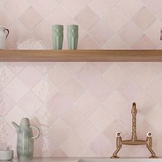 a kitchen with pink tiles and gold faucets on the shelf above the sink