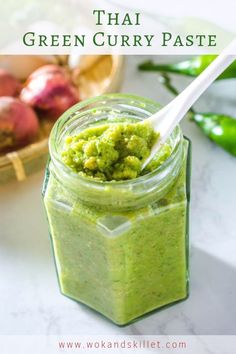 a jar filled with green curry paste next to some vegetables