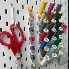 several spools of thread and scissors on a pegboard