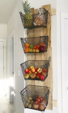 three metal baskets filled with fruit hanging on a wall